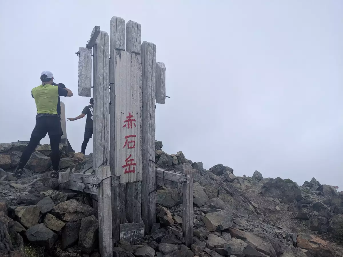 明石岳山頂標識と登山者
